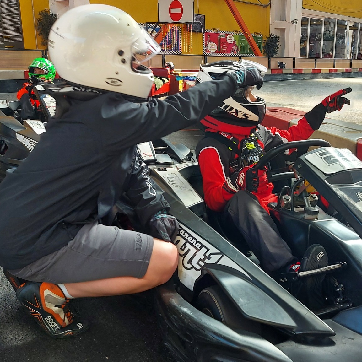 Coach zeigt einem Fahrer im Kart die Ideallinie